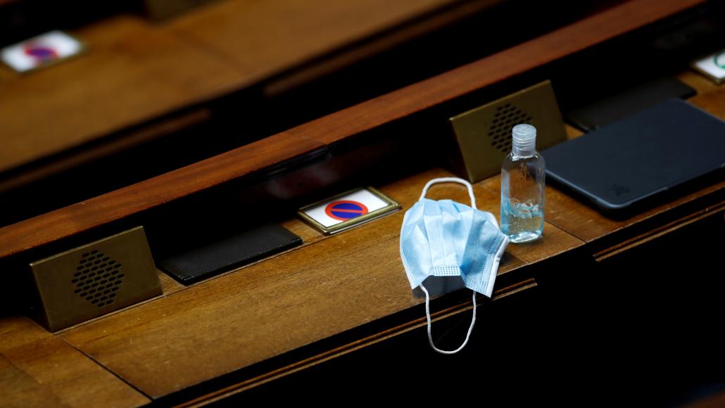 Un masque chirurgical et du gel hydroalcoolique posés sur un pupitre pendant les Questions au gouvernement, le 12 mai 2020 (Gonzalo Fuentes/AFP)