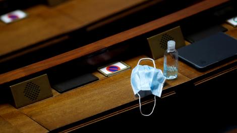 Un masque chirurgical et du gel hydroalcoolique posés sur un pupitre pendant les Questions au gouvernement, le 12 mai 2020 (Gonzalo Fuentes/AFP)