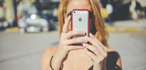 Une femme tient un téléphone portable dans la rue (© PublicDomainPictures)